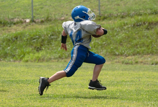 A youth football player running with ball.